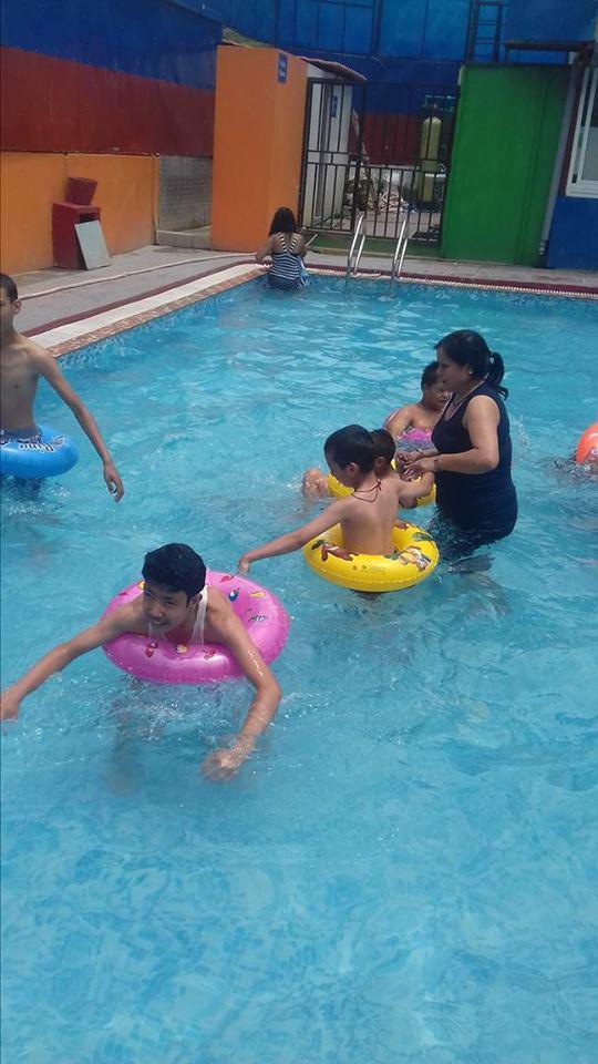 The teacher helping the children to swim